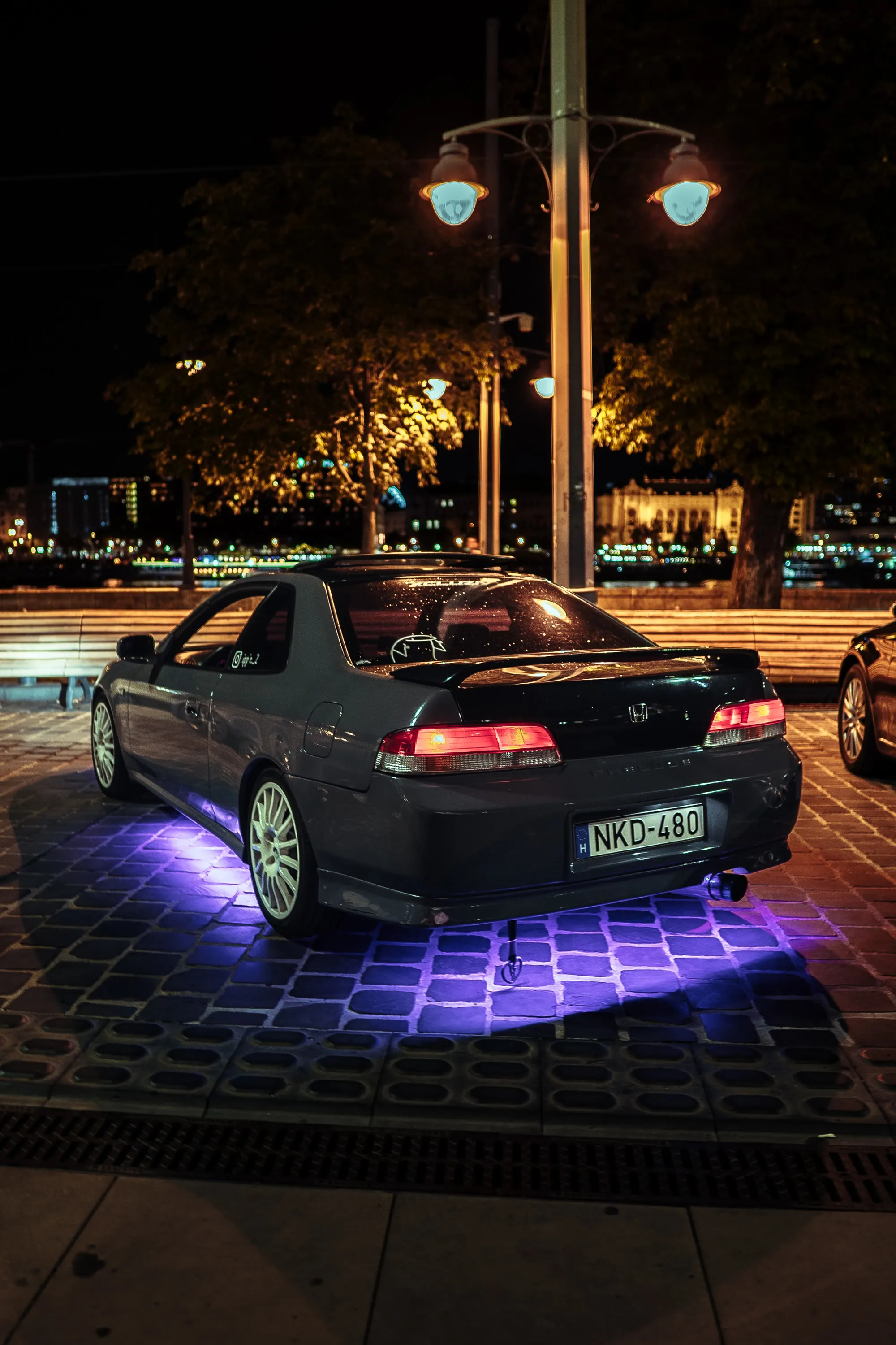 A Honda Prelude parked at night on cobblestones in Budapest